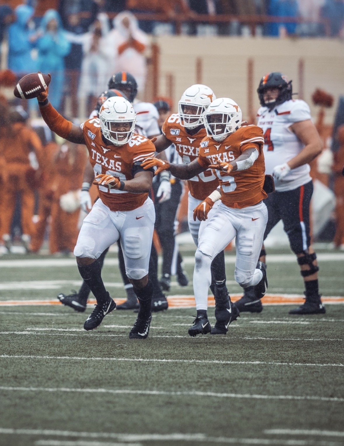 Marqez Bimage in a burnt-orange Texas Longhorns uniform, number 42, holding the football overhead while celebrating a turnover with teammates
